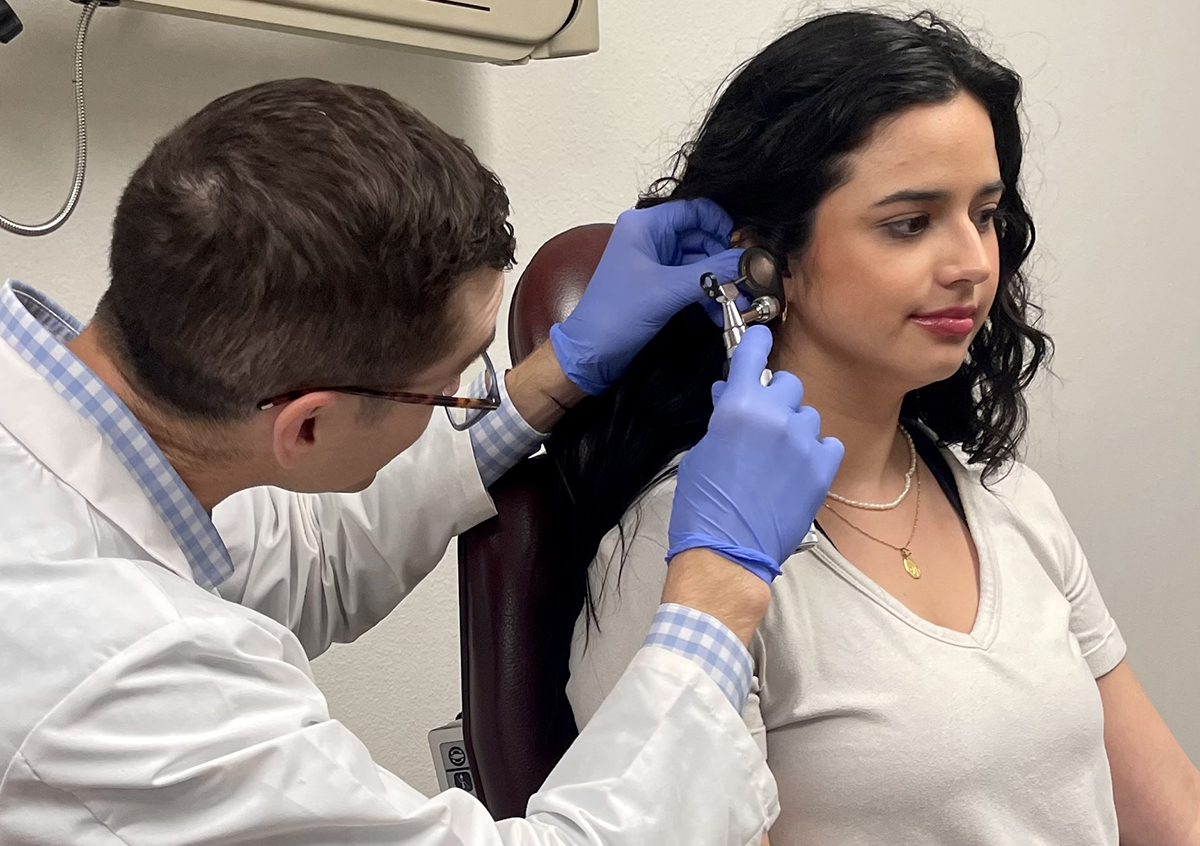A Scotch ENT physician examining a patient's ear